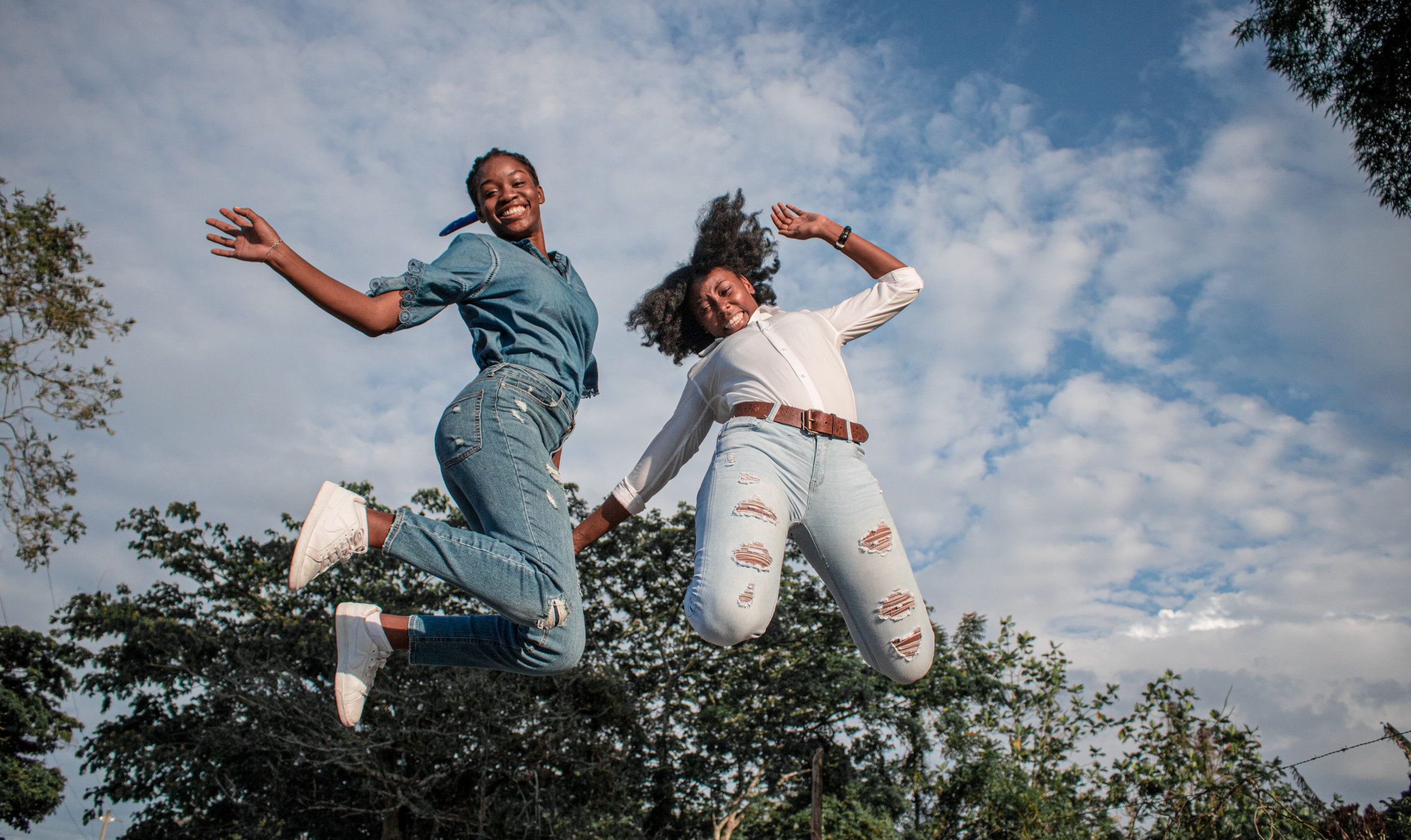 Energetic happy black women jumping in summer forest